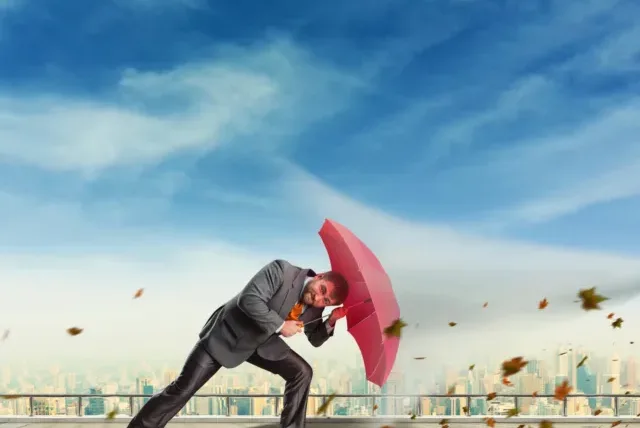 Businessman protects himself from rocks with umbrella